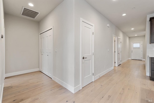 hallway featuring light wood-style flooring, visible vents, baseboards, and recessed lighting