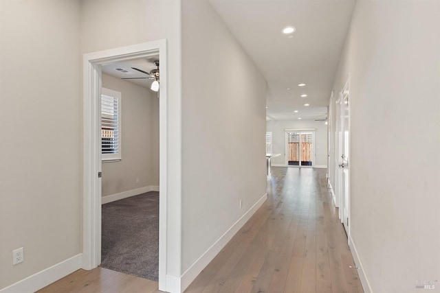 hall with recessed lighting, wood-type flooring, and baseboards