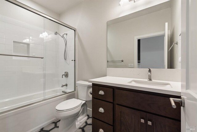 bathroom featuring combined bath / shower with glass door, vanity, toilet, and tile patterned floors