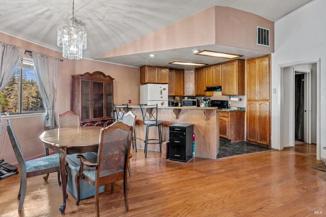 dining space with a chandelier, light hardwood / wood-style floors, and vaulted ceiling