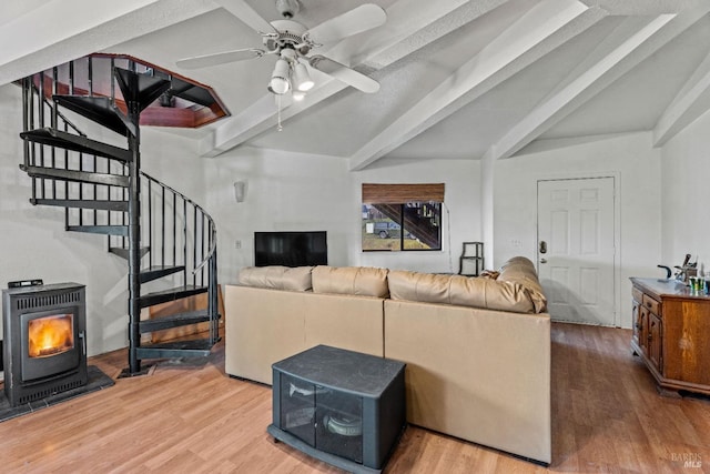 living room featuring beam ceiling, a wood stove, ceiling fan, and hardwood / wood-style floors