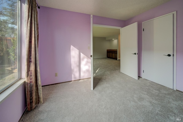 spare room featuring light colored carpet and a textured ceiling