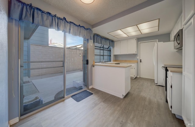 kitchen with range with electric cooktop, light hardwood / wood-style flooring, white cabinets, and a textured ceiling