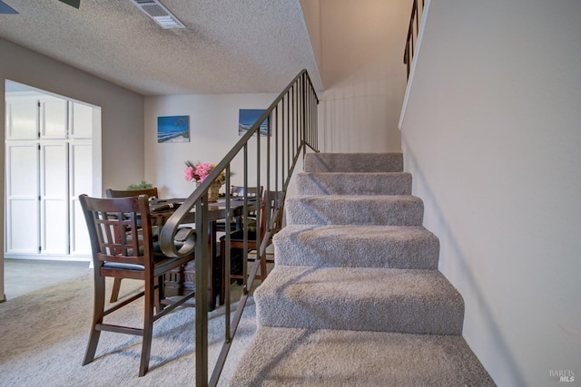 stairs featuring carpet and a textured ceiling