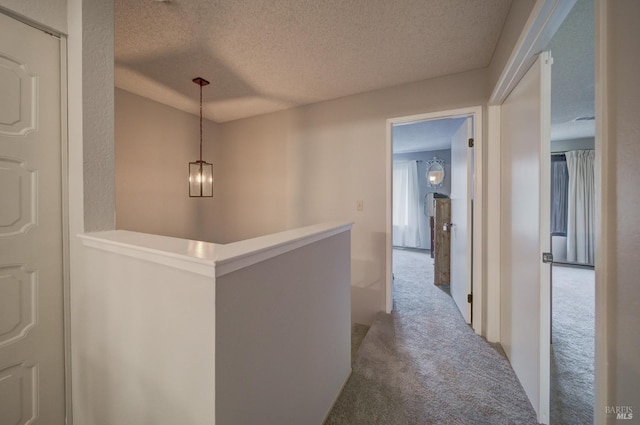 hallway featuring carpet flooring and a textured ceiling