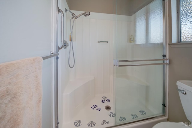 bathroom featuring toilet and a shower with shower door