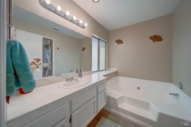 bathroom with a washtub, hardwood / wood-style floors, and vanity