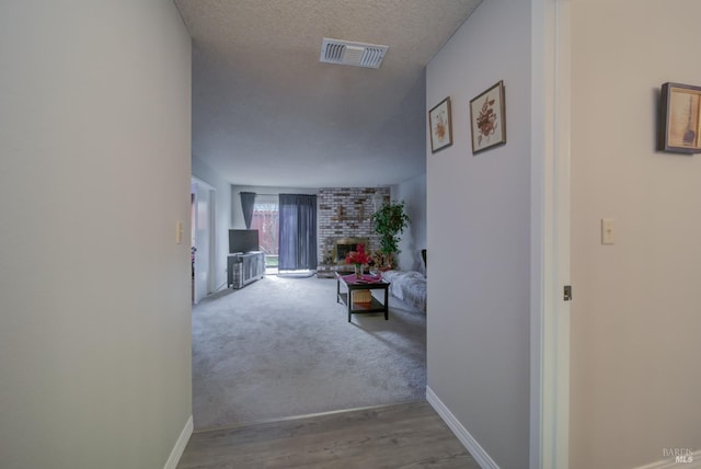 corridor featuring light wood-type flooring and a textured ceiling