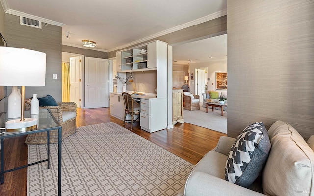 living room with dark hardwood / wood-style floors, built in desk, and ornamental molding