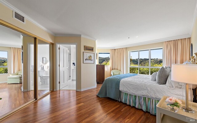 bedroom featuring ensuite bath, multiple windows, dark wood-type flooring, and crown molding