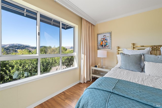 bedroom featuring a mountain view, hardwood / wood-style flooring, and ornamental molding