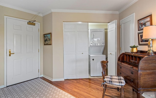 foyer featuring stacked washing maching and dryer, ornamental molding, and light hardwood / wood-style flooring