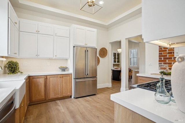 kitchen featuring stainless steel appliances, white cabinetry, a raised ceiling, and light hardwood / wood-style floors