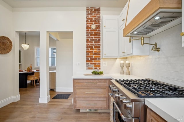 kitchen with premium range hood, white cabinetry, tasteful backsplash, high end stainless steel range, and decorative light fixtures