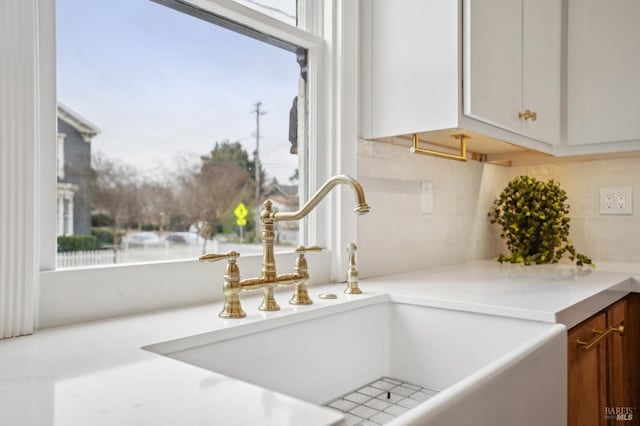 room details featuring white cabinetry, sink, and decorative backsplash