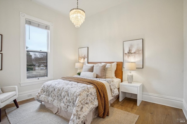 bedroom with light hardwood / wood-style flooring and a chandelier