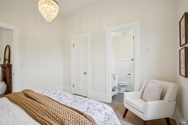 bedroom featuring hardwood / wood-style flooring, connected bathroom, and a chandelier