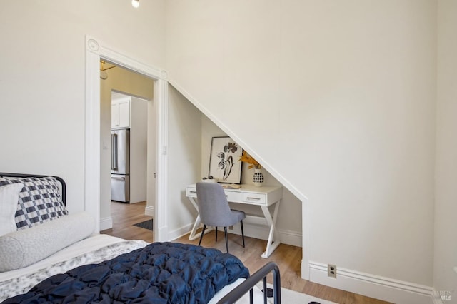 bedroom with high end fridge and light hardwood / wood-style flooring