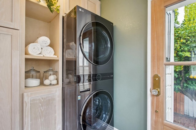 laundry room featuring cabinets and stacked washer / drying machine