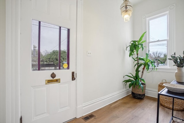 doorway to outside with hardwood / wood-style flooring and an inviting chandelier