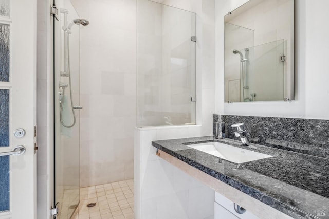 bathroom featuring a shower with shower door and sink