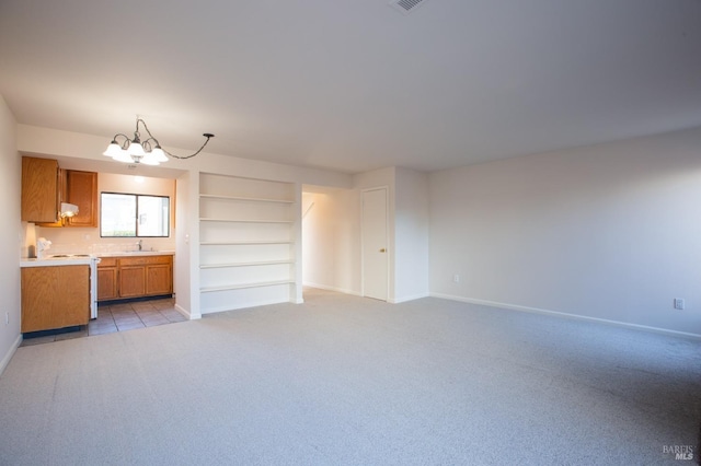 unfurnished living room featuring light carpet, a notable chandelier, and sink