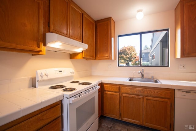 kitchen with tile countertops, dark tile patterned floors, white appliances, and sink