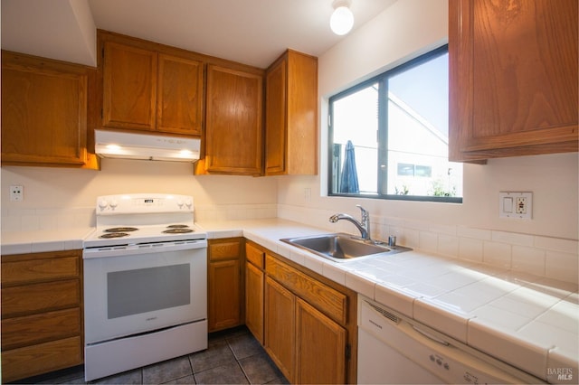 kitchen with tile counters, dark tile patterned floors, white appliances, and sink