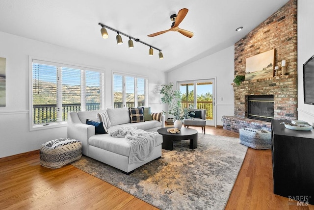 living room with a fireplace, wood-type flooring, vaulted ceiling, and ceiling fan