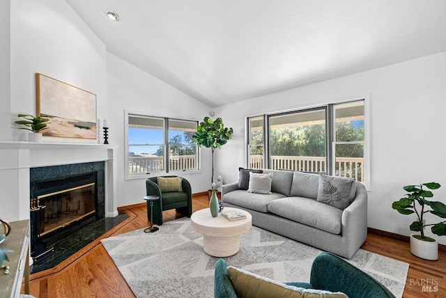 living room with hardwood / wood-style floors, a high end fireplace, and vaulted ceiling