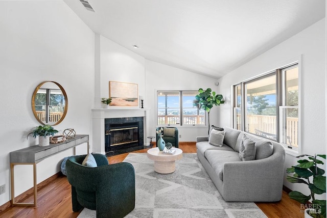 living room with hardwood / wood-style flooring, vaulted ceiling, and a premium fireplace