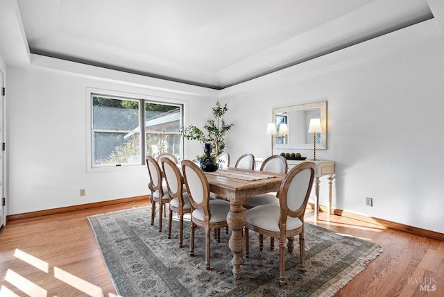 dining area featuring light hardwood / wood-style floors and a raised ceiling