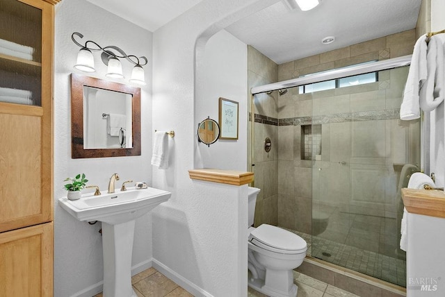 bathroom with tile patterned floors, a shower with shower door, a textured ceiling, and toilet