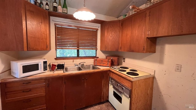 kitchen with white appliances, decorative light fixtures, lofted ceiling, and sink