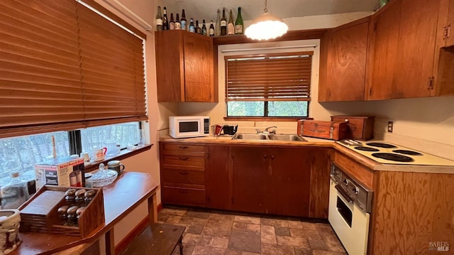 kitchen featuring sink, white appliances, and hanging light fixtures