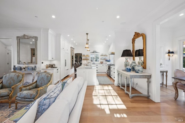 living room featuring sink, light hardwood / wood-style floors, and ornamental molding