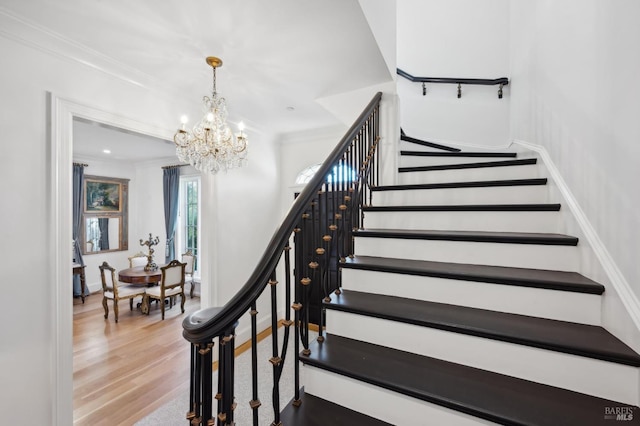 stairs with hardwood / wood-style flooring, a notable chandelier, and crown molding