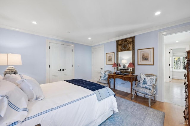 bedroom featuring wood-type flooring, ornamental molding, and a closet