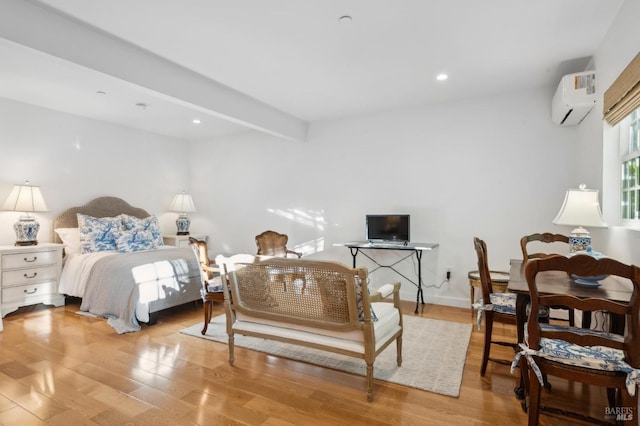 bedroom featuring beamed ceiling, light hardwood / wood-style flooring, and a wall mounted AC