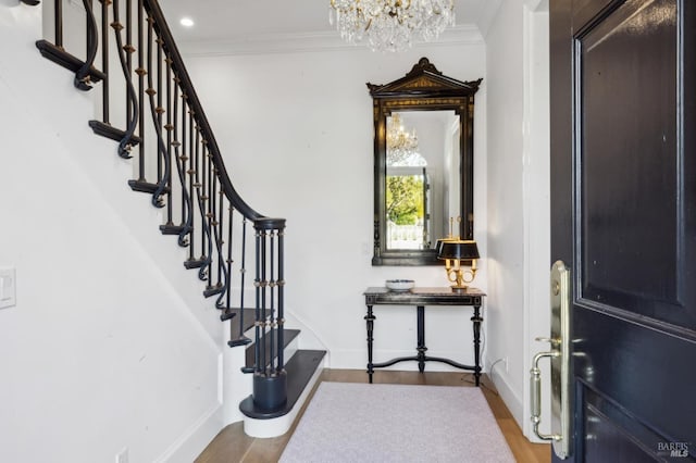 foyer entrance featuring a chandelier, hardwood / wood-style floors, and crown molding