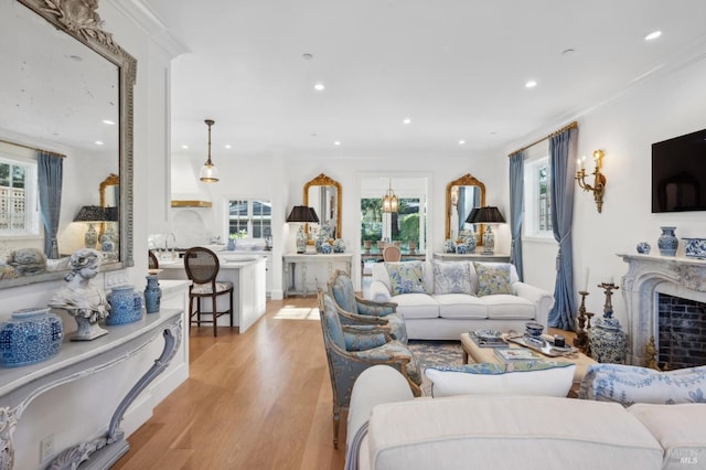 living room featuring light wood-type flooring, ornamental molding, and a high end fireplace