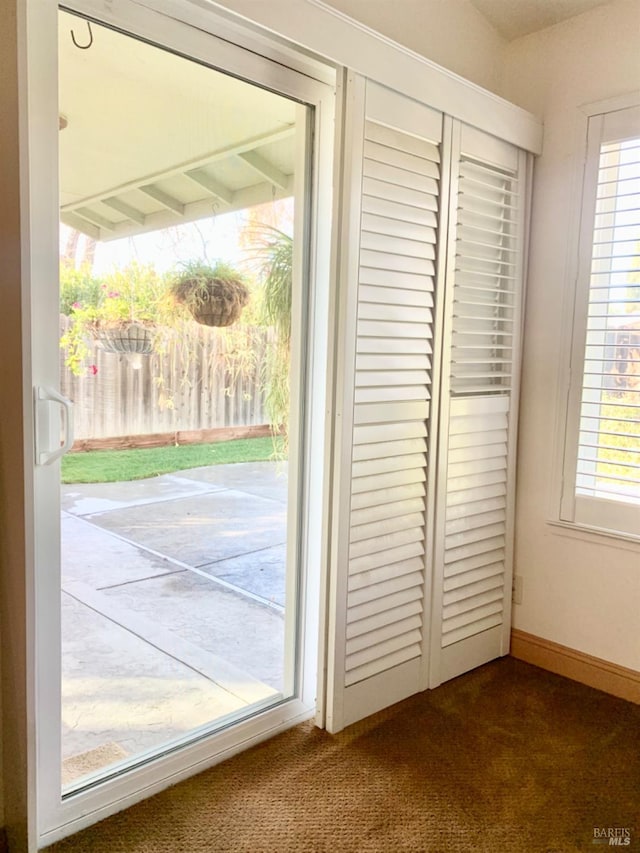 doorway to outside with a healthy amount of sunlight, dark carpet, and baseboards