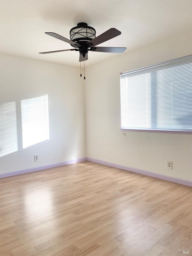 spare room with ceiling fan, plenty of natural light, and light wood-type flooring