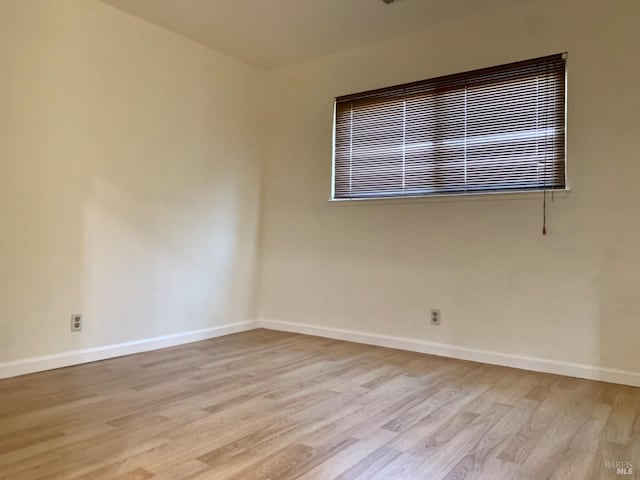 empty room featuring light wood finished floors and baseboards