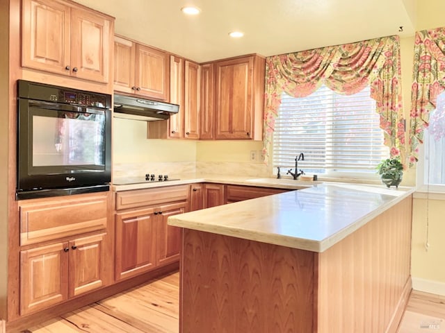 kitchen featuring sink, kitchen peninsula, light hardwood / wood-style floors, and black appliances