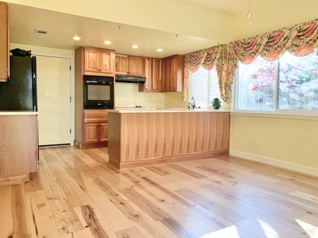 kitchen featuring light hardwood / wood-style flooring, kitchen peninsula, and black appliances