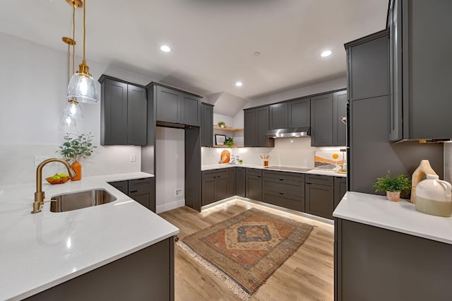 kitchen with gray cabinets, black electric stovetop, decorative light fixtures, light hardwood / wood-style flooring, and sink