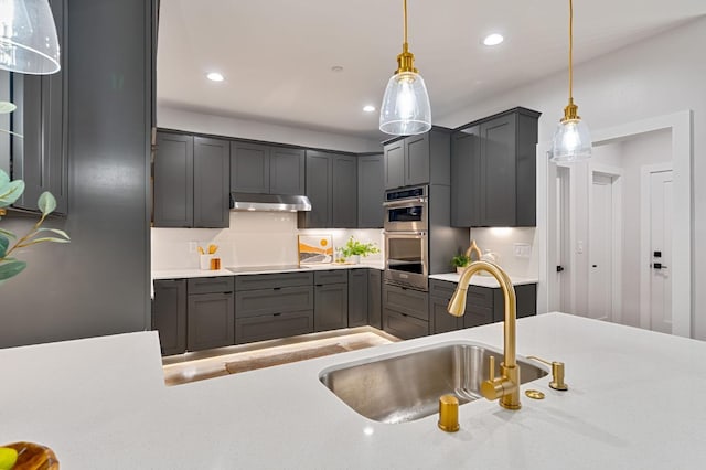 kitchen featuring cooktop, sink, stainless steel double oven, and decorative light fixtures