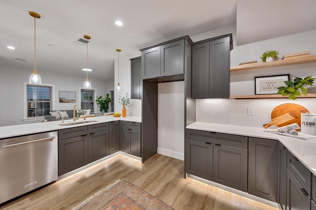 kitchen featuring stainless steel dishwasher, decorative light fixtures, sink, and light hardwood / wood-style flooring