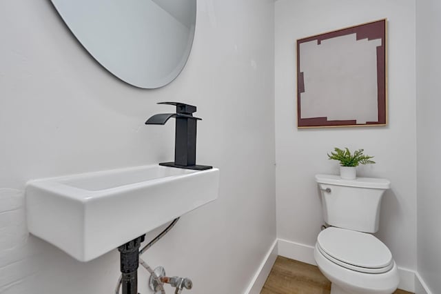 bathroom with toilet, hardwood / wood-style flooring, and sink